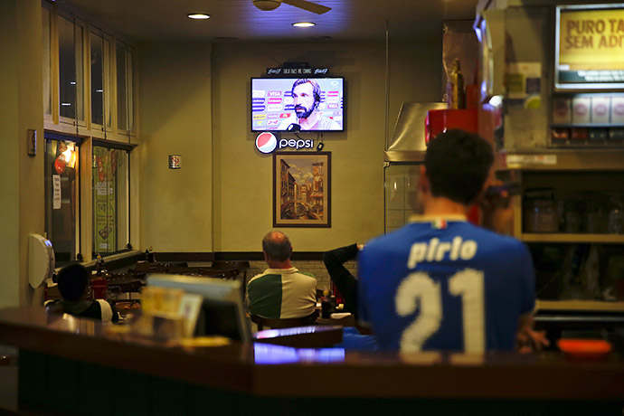 A Brazilian man of Italian origin wears a jersey of Andrea Pirlo as Andrea Pirlo appears on TV screen in a restaurant in Porto Alegre following Italy's win over England in a 2014 World Cup Group D match